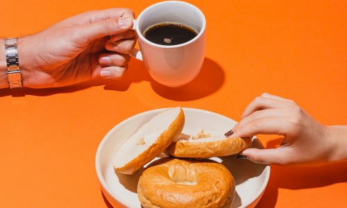 hands holding coffee and bagels